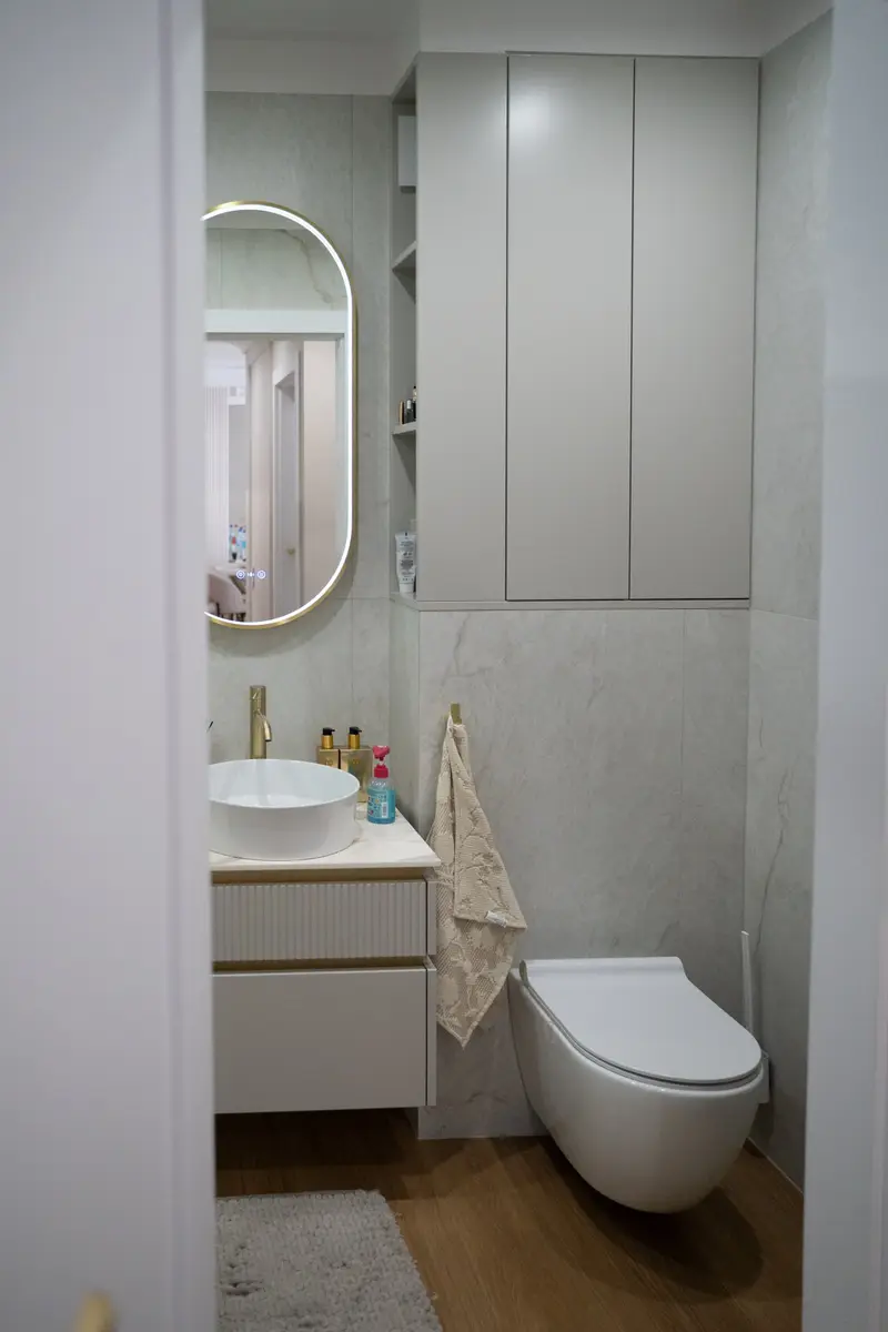 Łazienka z szafką do sufitu nad WC i wiszącą szafką pod umywalką